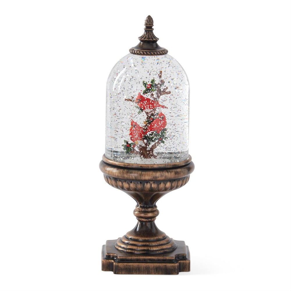 Glass dome snow globe featuring red cardinals on a branch set atop an ornate bronze pedestal.