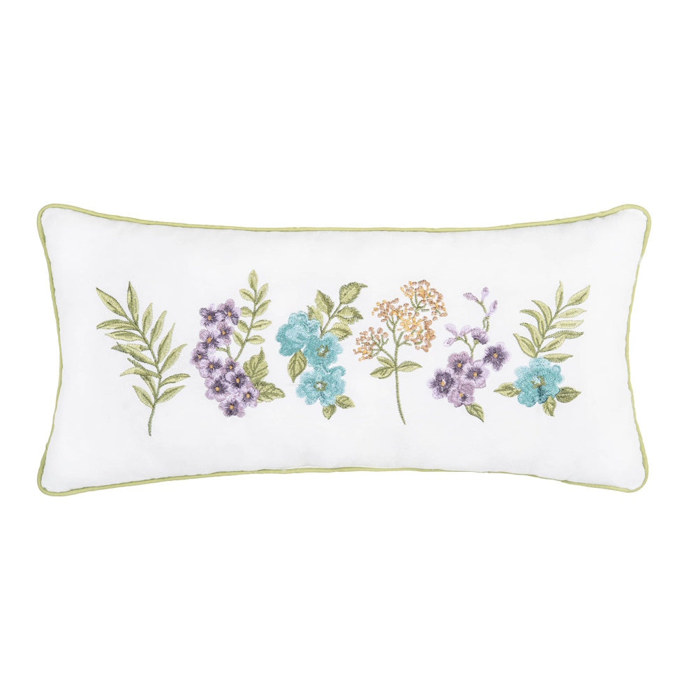 Lumbar pillow with embroidered wildflowers in purple, blue, and yellow with green leaves on a white background.