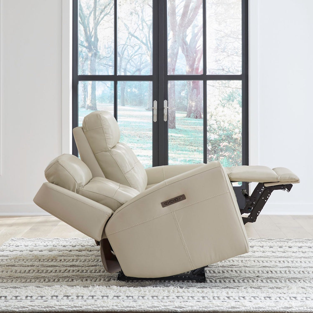 Cream leather power recliner sofa shown fully reclined with adjustable headrest and extended footrest in living room setting.