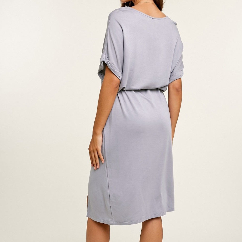 Back view of a woman wearing a casual, short-sleeved gray t-shirt midi dress with an elastic waist.