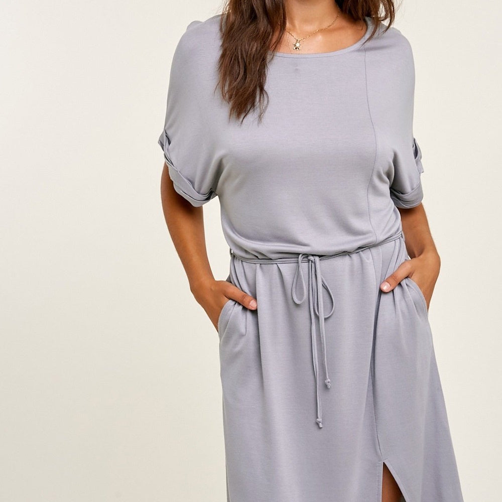 Close-up of a woman wearing a light gray t-shirt midi dress with a drawstring waist and pockets.