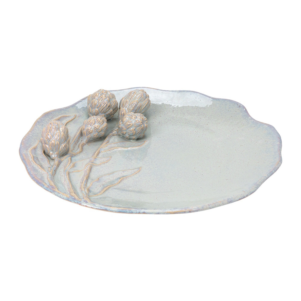 Irregular light blue ceramic platter with raised artichoke designs and a wavy edge on a white background.