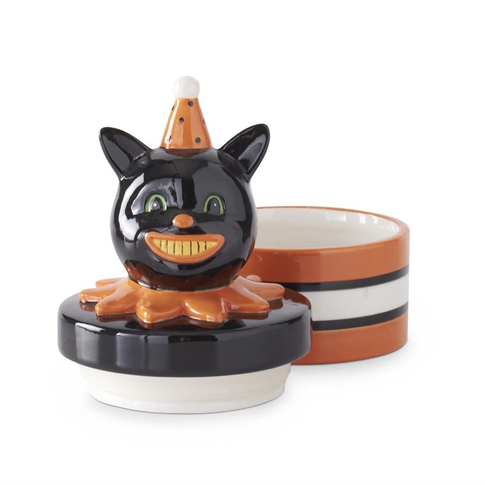 An open ceramic black cat canister with a smiling vintage cat head lid resting next to its striped base.