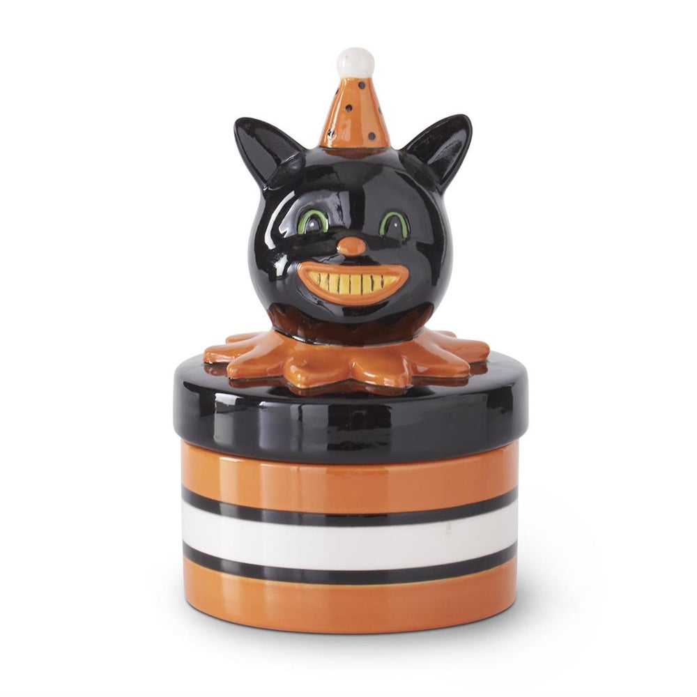 A vintage-style ceramic black cat canister wearing a party hat on a striped base on white background.