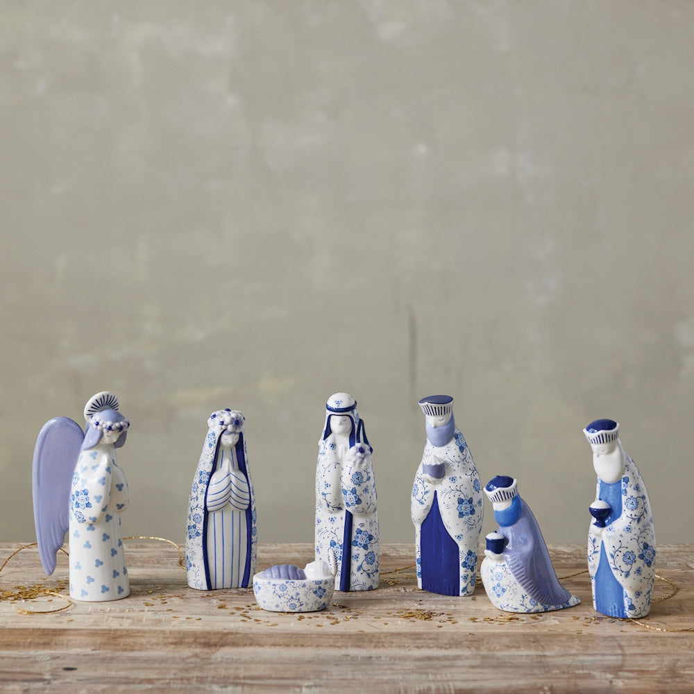 Blue and white ceramic nativity set with floral patterns displayed on a wooden surface.
