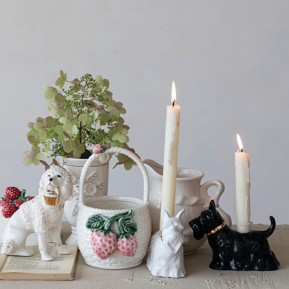 Black and white ceramic Scottie dog taper holders with lit candles and vintage table decor.