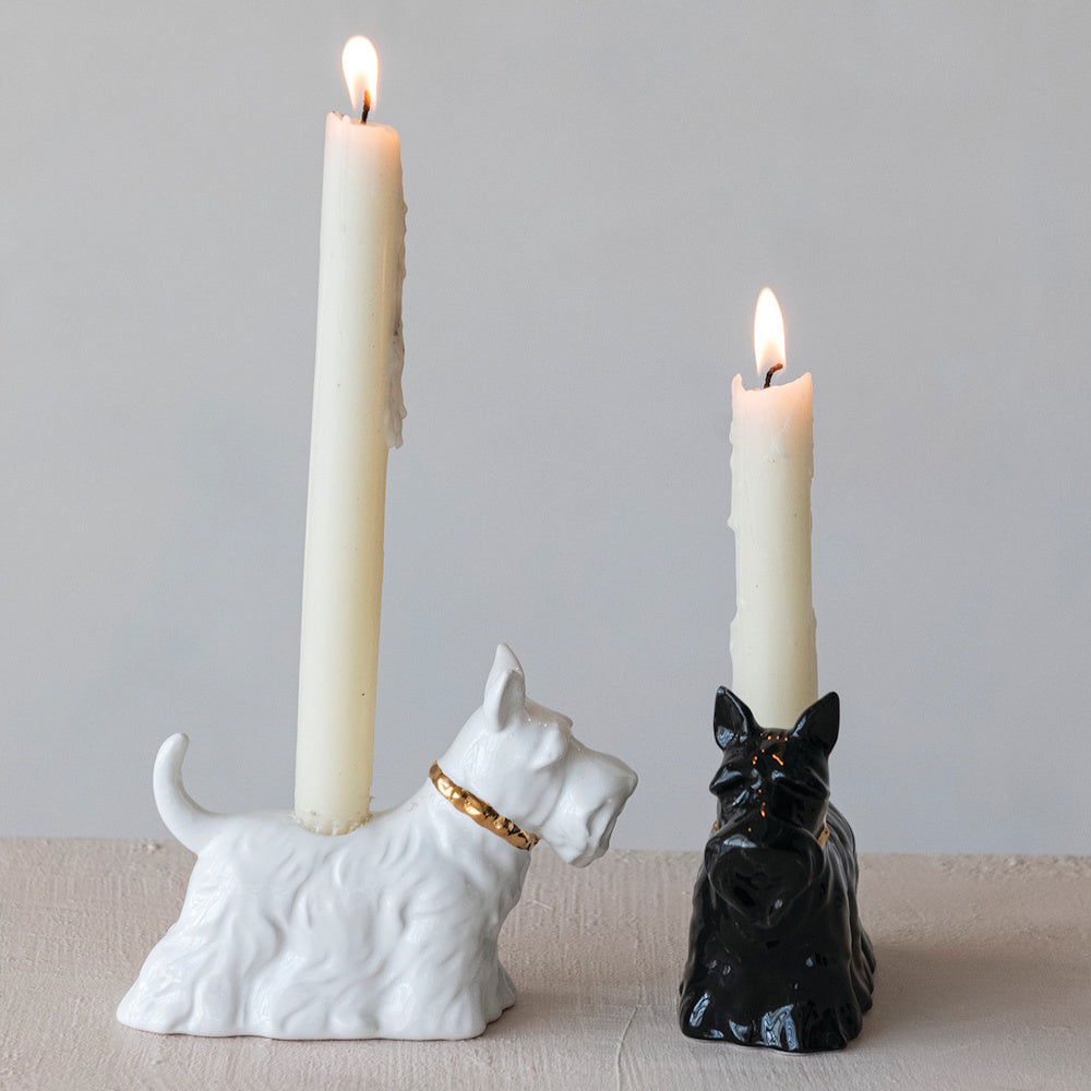 Black and white ceramic Scottie dog taper candle holders with lit candles.