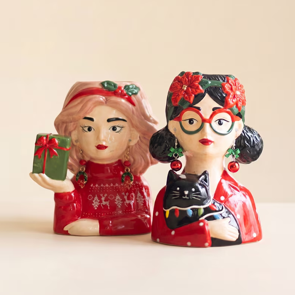Pair of festive ceramic woman head vases wearing holiday sweaters and Christmas accessories.