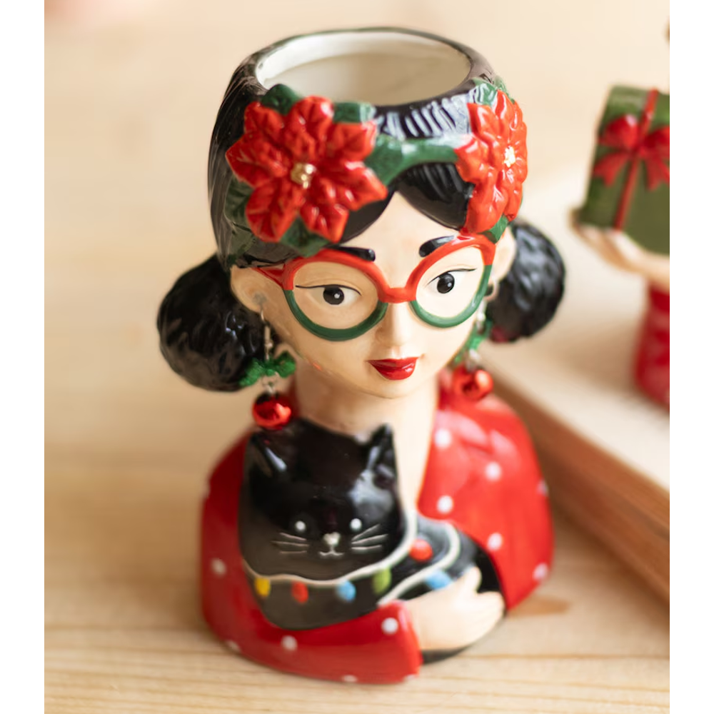 Ceramic woman head vase with red-and-green glasses, holding a black cat in a holiday sweater.