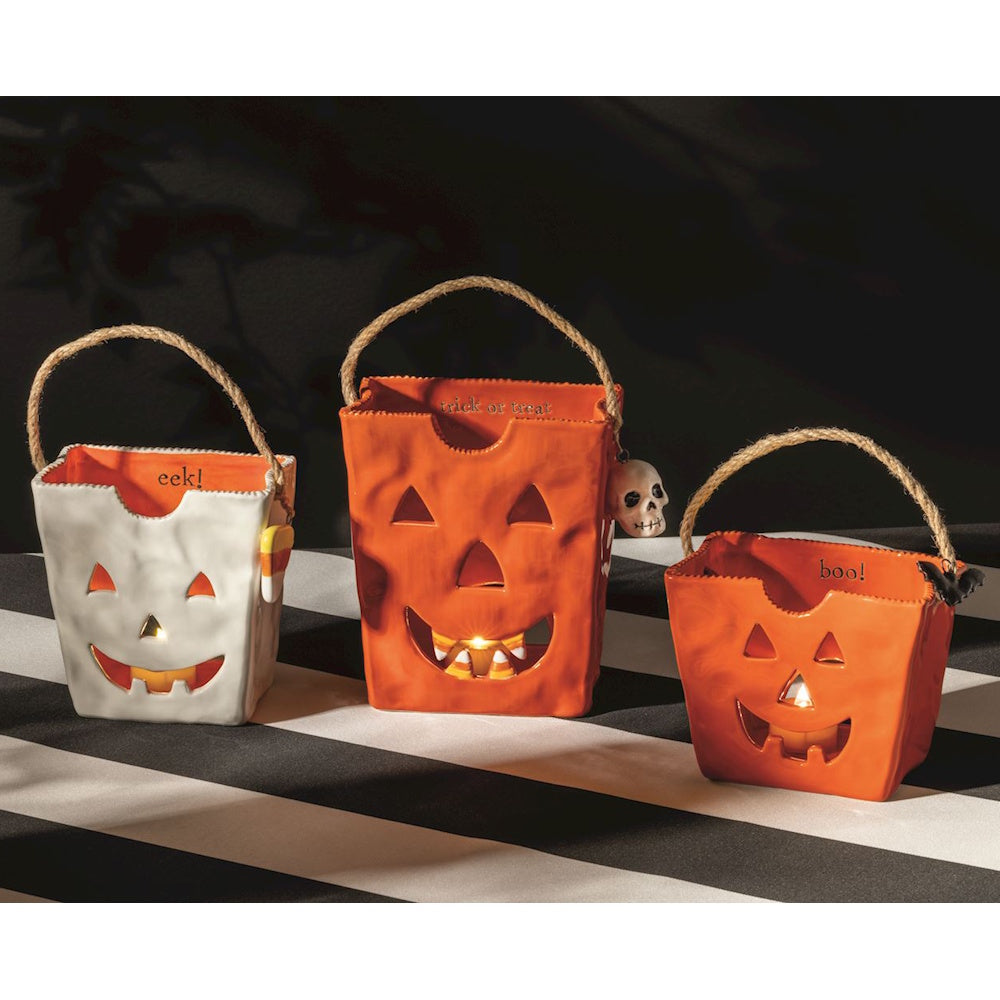 Three ceramic Halloween treat bag lanterns with jack-o'-lantern faces and twine handles.