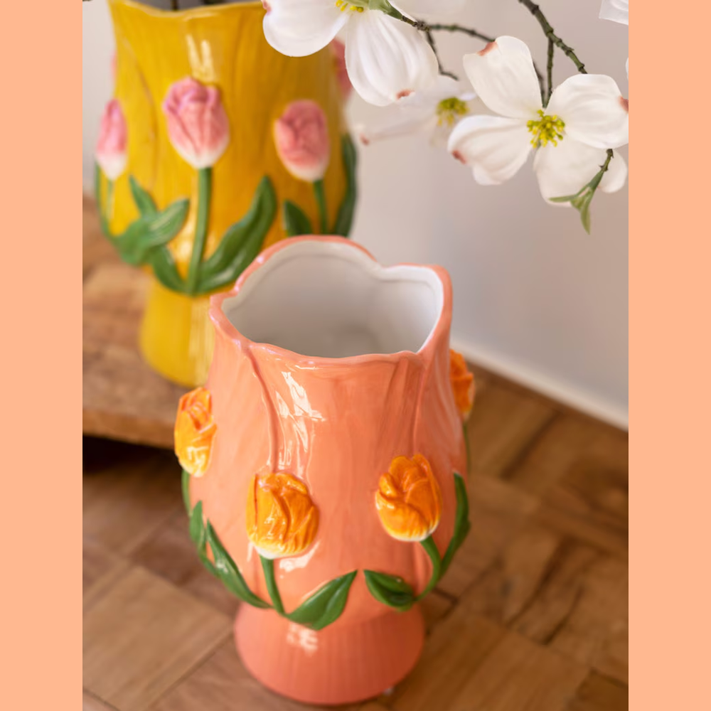 Peach and yellow ceramic tulip-shaped vases with 3D floral details on a wooden surface.
