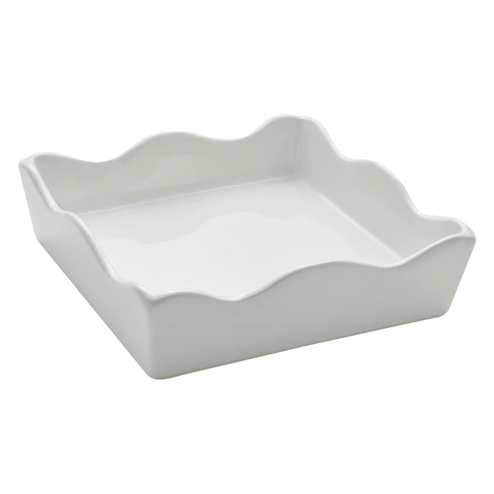 Side angle view of a white ceramic cocktail napkin tray with a wavy rim style.