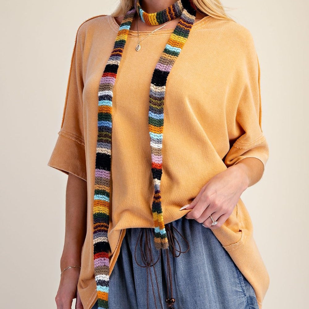 Yellowish-orange short-sleeved terry knit top styled with a colorful striped skinny scarf.
