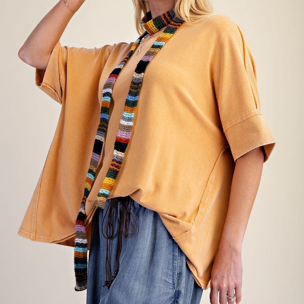 Model wearing a loose-fitting yellow knit top paired with a colorful striped skinny scarf.