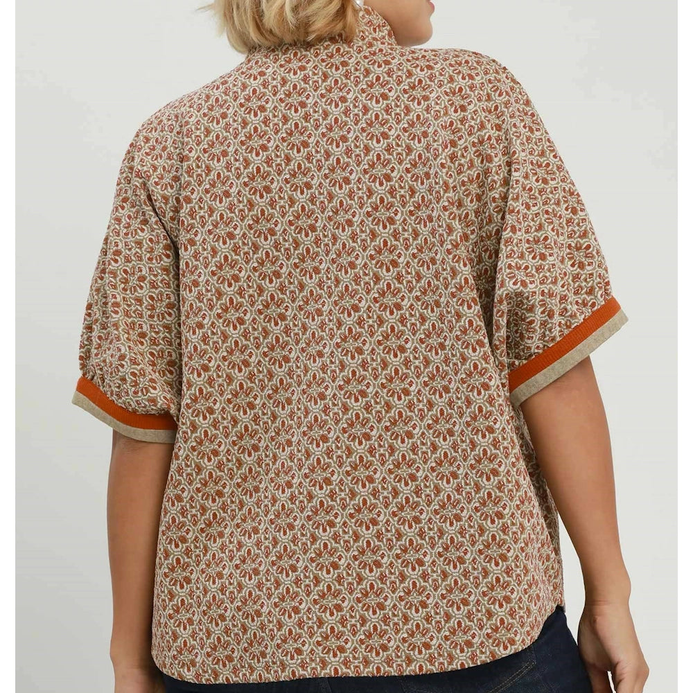 Back view of a woman wearing a chestnut geometric print blouse with short cuff-trimmed sleeves.
