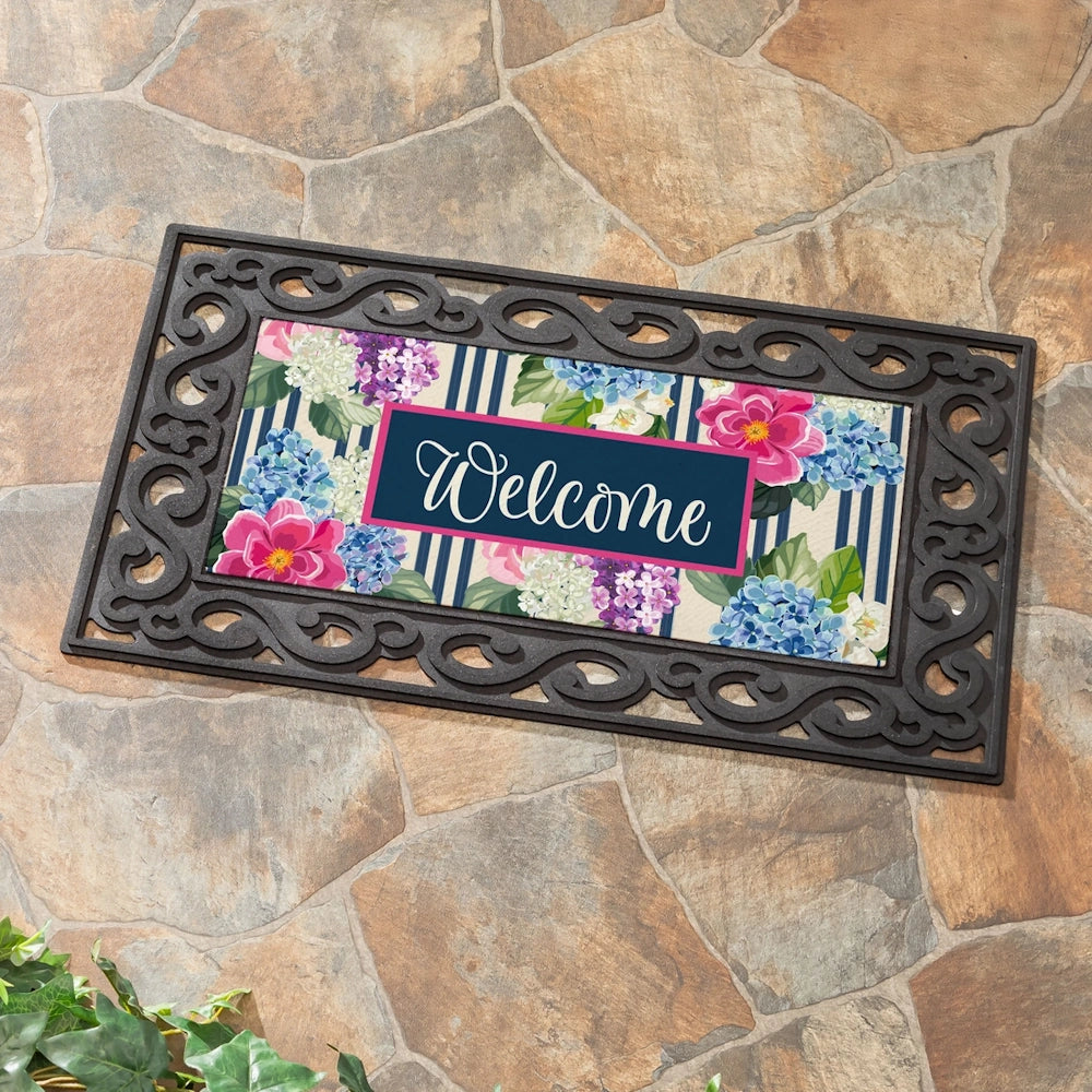 Floral Welcome doormat with hydrangeas and Chinoiserie pattern on a stone porch, featuring a scrollwork rubber frame.