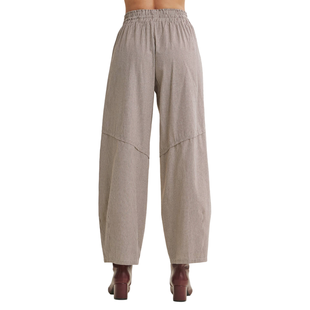 Back view of brown striped relaxed-fit barrel pants with an elastic waistband, styled with dark heeled boots.