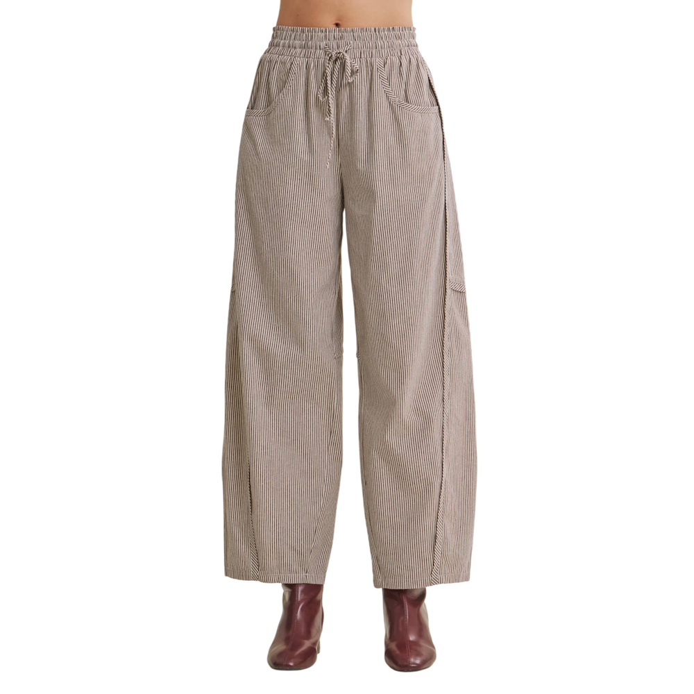 Front view of brown pinstriped drawstring barrel pants featuring side pockets and dark leather boots.