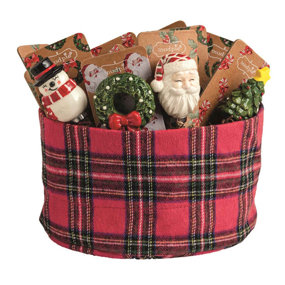 Holiday ceramic cheese spreaders displayed inside a red plaid fabric bin.