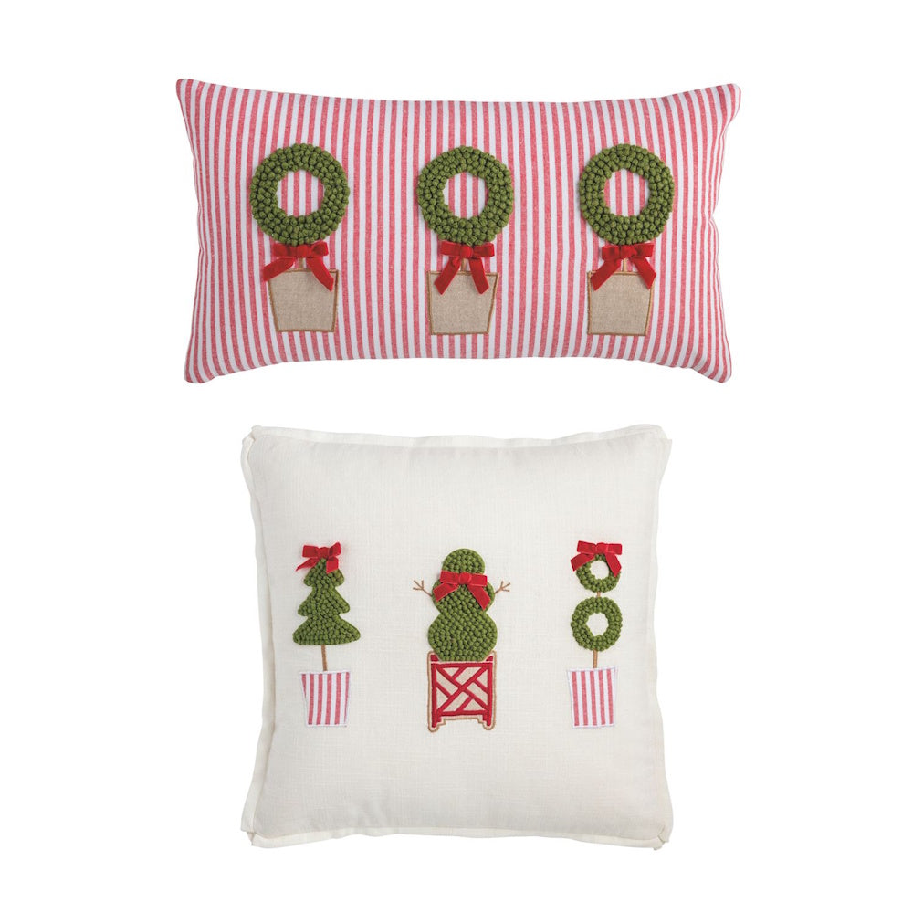 Two Christmas pillows featuring topiary designs, including a red-striped lumbar pillow with wreaths and a square white pillow with various topiary trees.