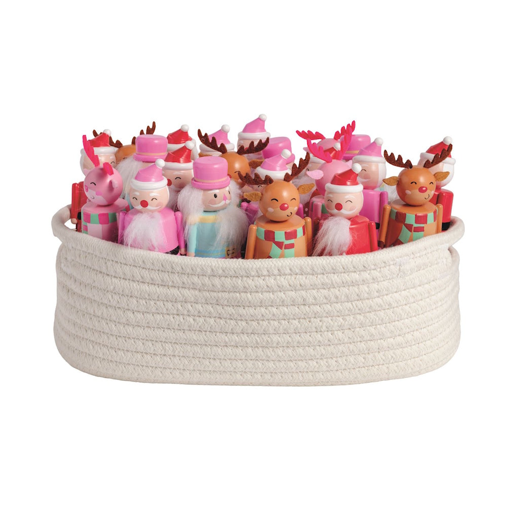 Woven rope basket filled with festive pink and red Christmas wind-up figures on a white background.
