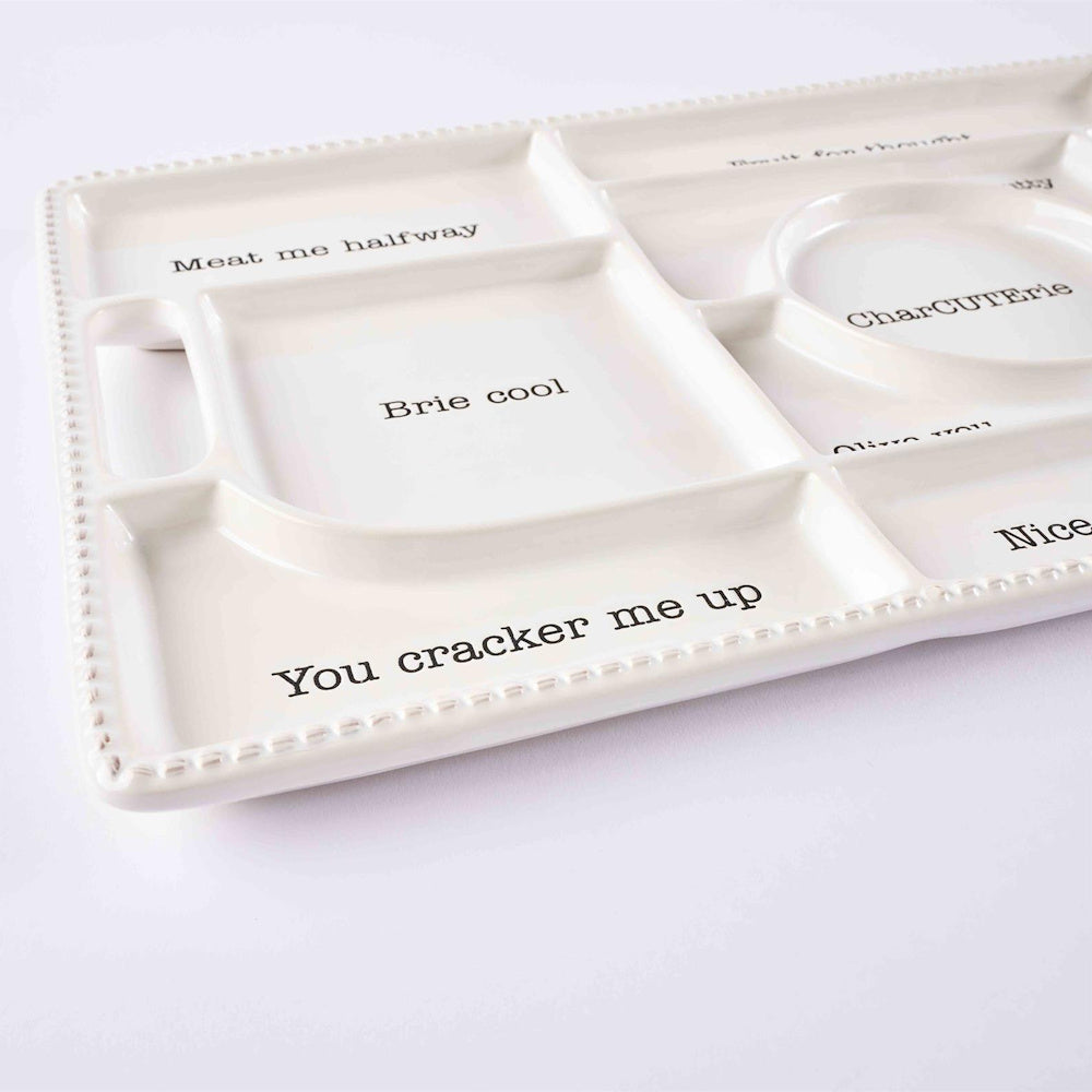White ceramic sectional charcuterie tray with food puns like "Brie cool" and "You cracker me up" in black text.