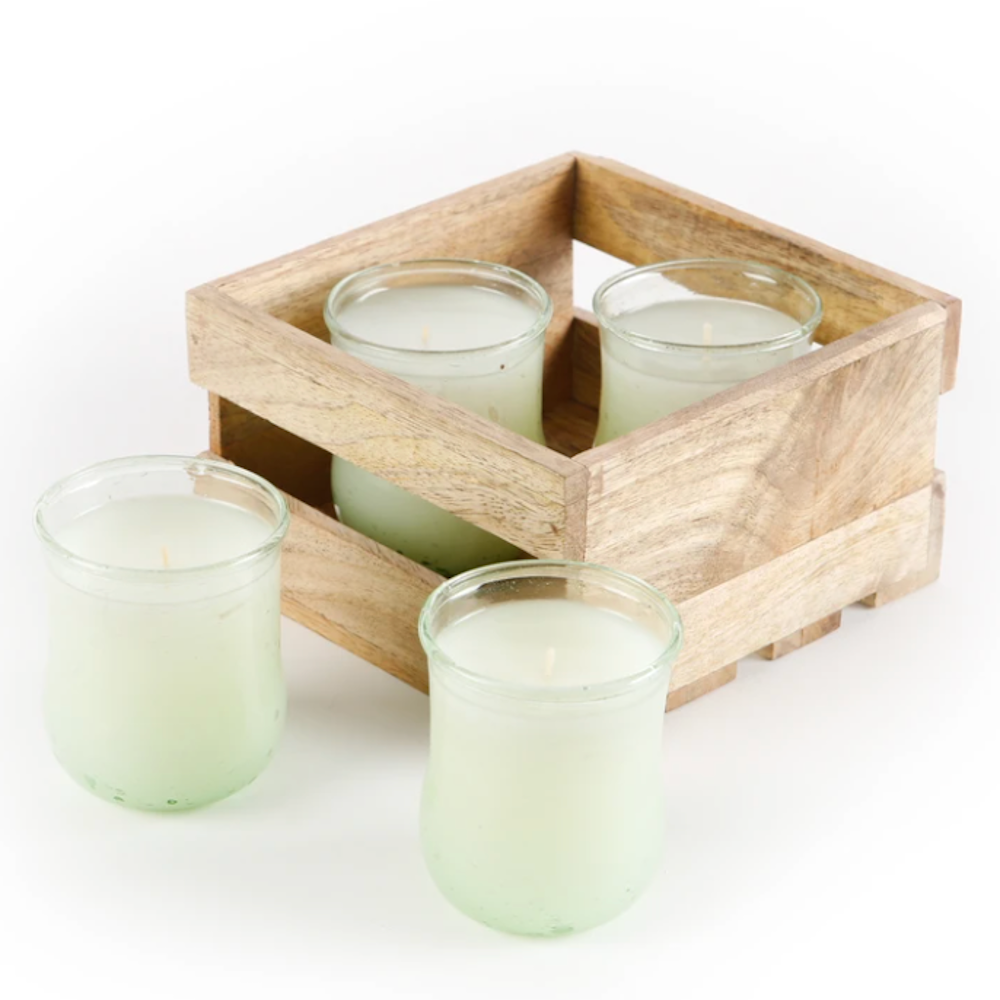Four light green candles in glass jars, two sitting inside a small wooden crate and two placed out front.