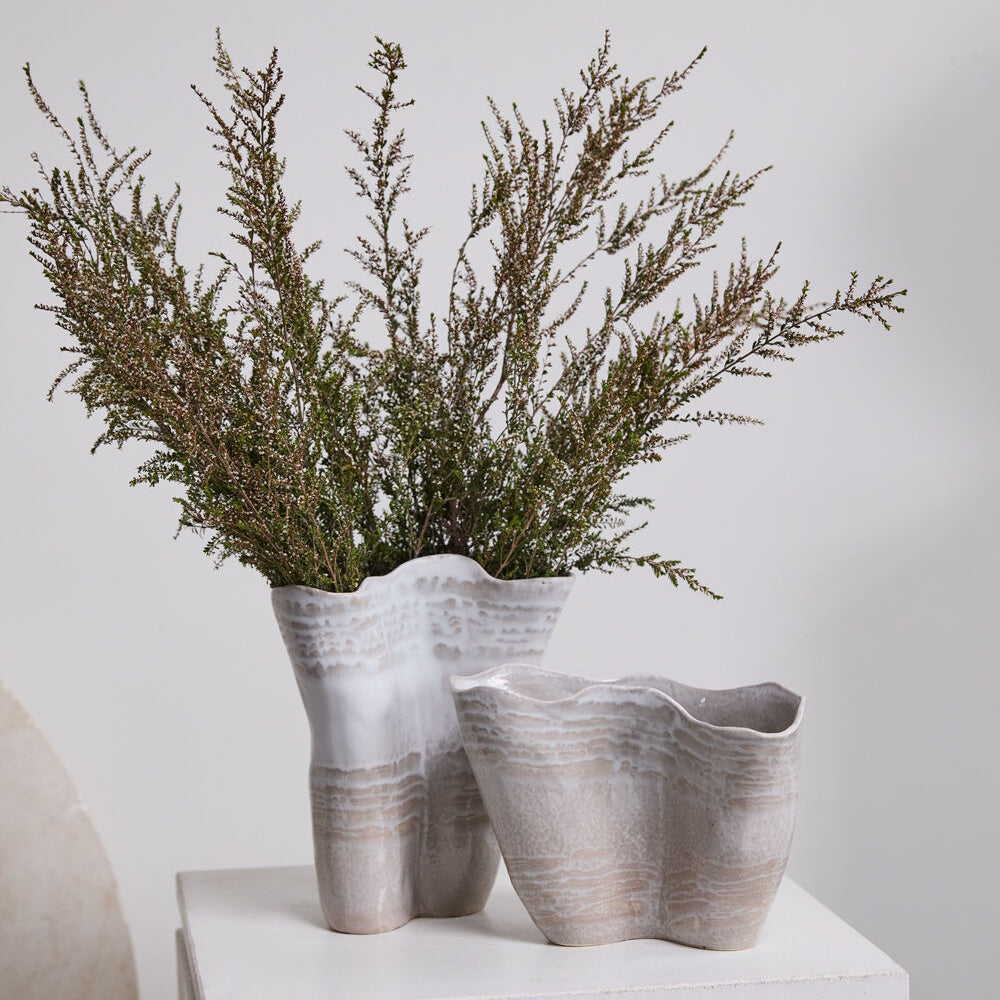 Two ceramic vases with wavy rims and a textured, sandy-white glaze, one holding dried branches.