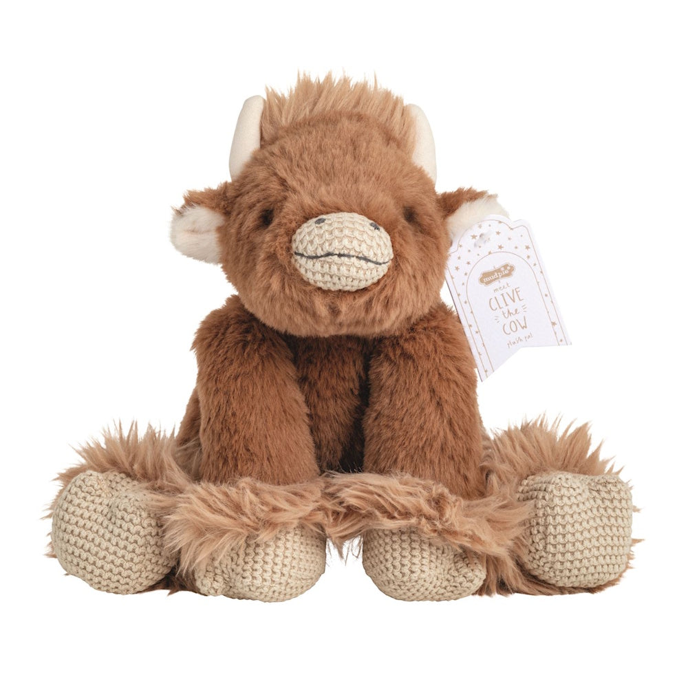 Brown highland cow plush toy with fuzzy fur, small horns, and knit hooves, featuring a "Clive the Cow" Mud Pie tag.