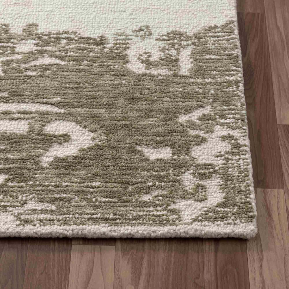 Close-up of a Nuvia hand-tufted rug featuring a textured, sage green and ivory distressed pattern on wood floors.