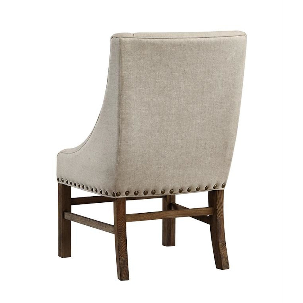 Back view of a beige linen accent chair with nailhead trim and a dark wood frame.
