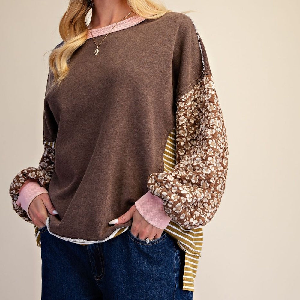 Side angled view of coffee brown terry knit pullover with floral sleeves and pink ribbed cuffs.