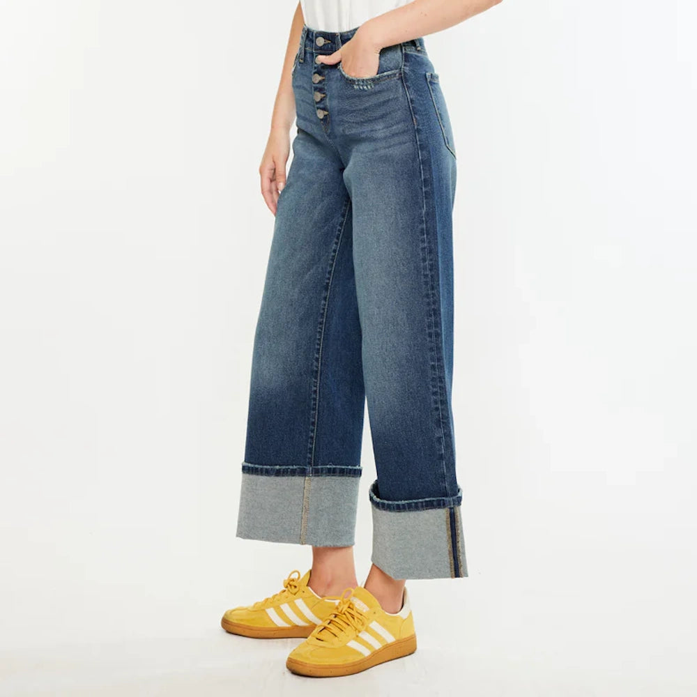 Ultra high-rise crop wide-leg jeans in a medium wash with oversized cuffs, paired with yellow sneakers.