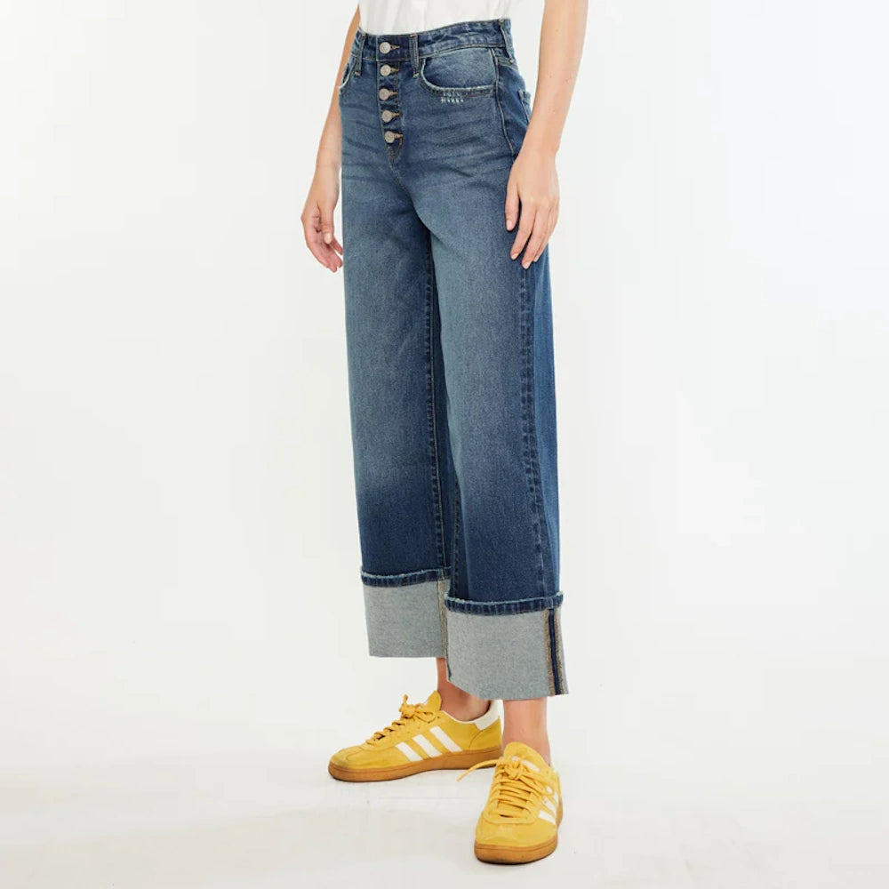 Wide-leg cropped denim with a high-rise button fly and oversized cuffs, paired with yellow sneakers on a white background.