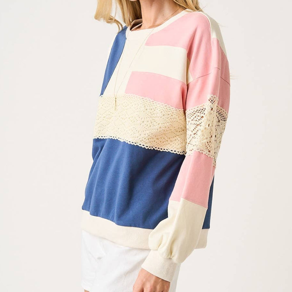 Oversized color-block sweatshirt in blue, pink, and cream with lace crochet detail, shown from a side view.