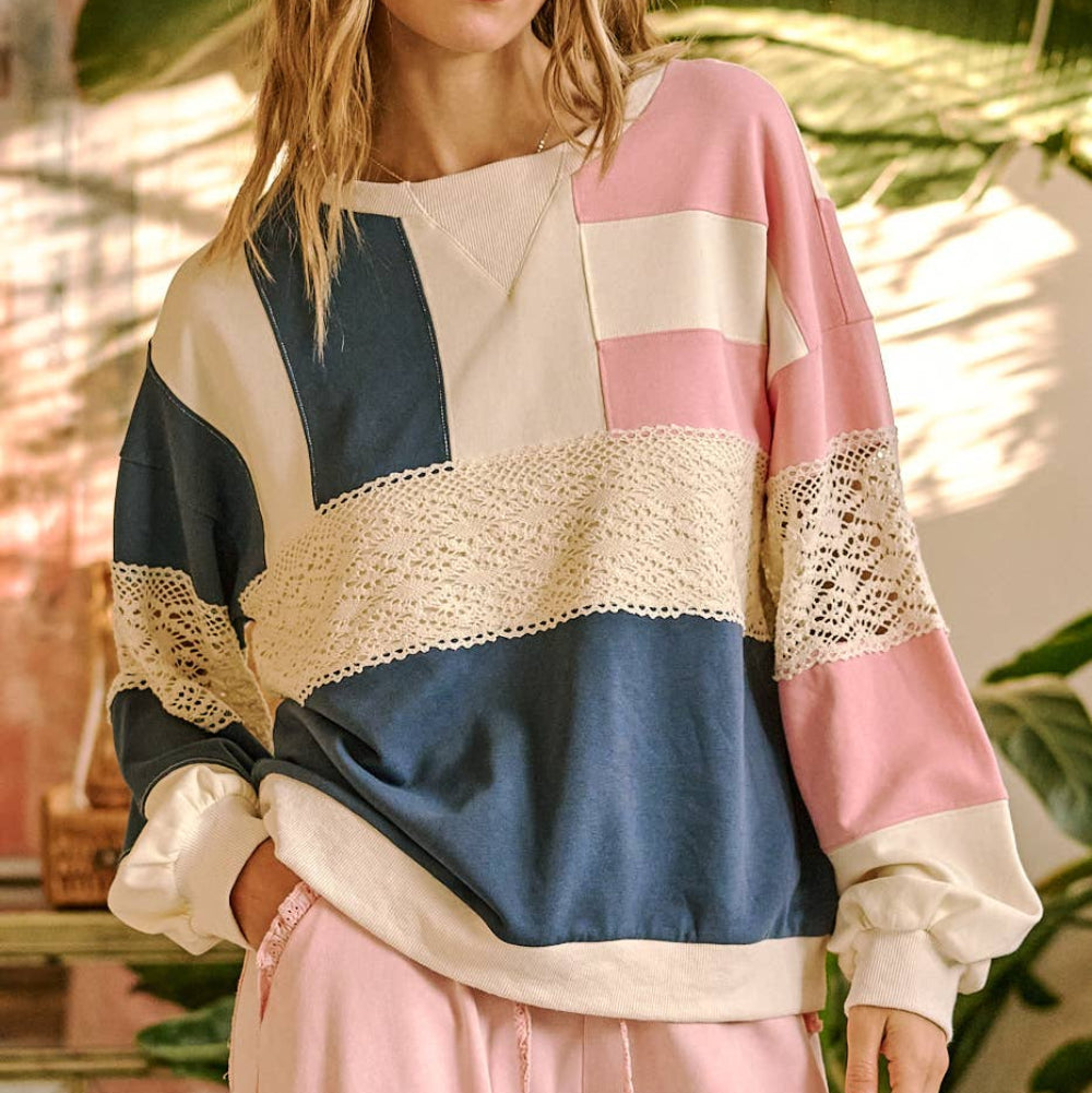 Oversized color-block sweatshirt in blue, pink, and cream with horizontal white lace crochet detailing.