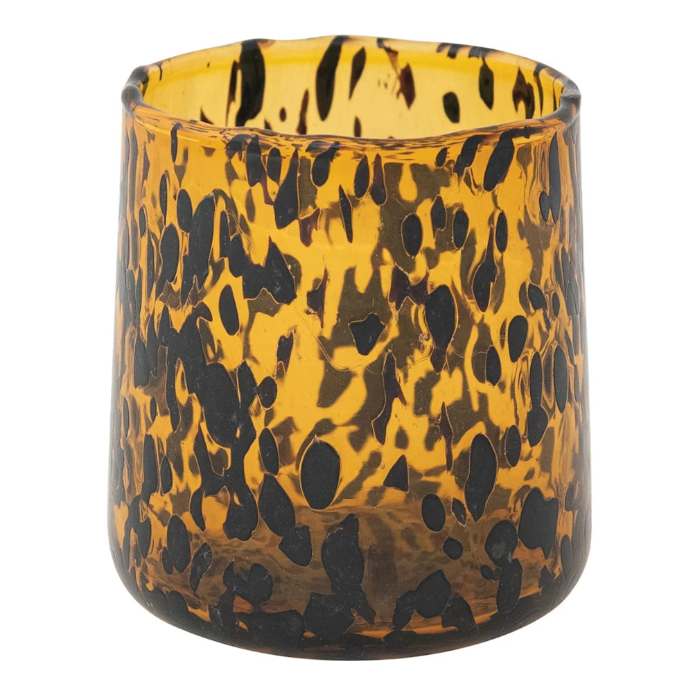 Handblown amber tortoise shell pattern drinking glass with black confetti spots on a white background.