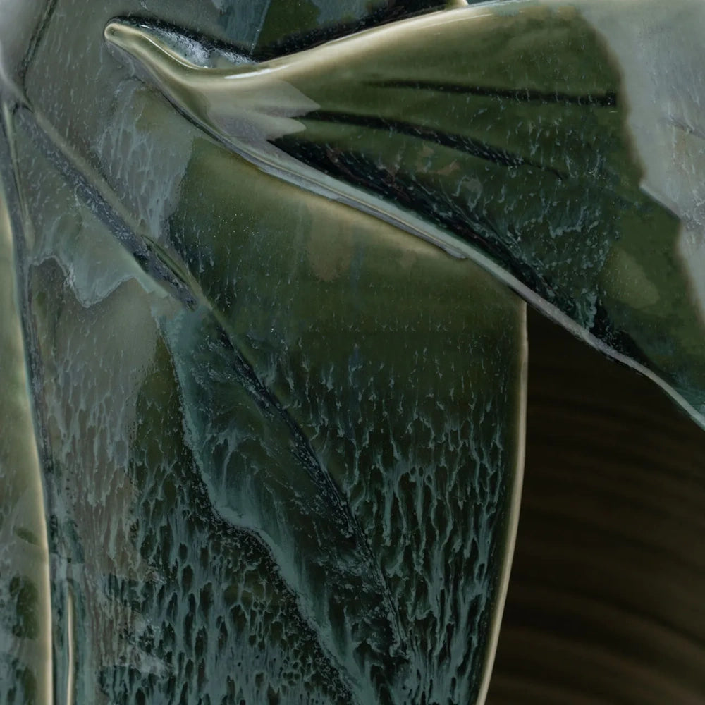 Close-up of a glossy green ceramic vase with a textured, drip-glaze pattern mimicking organic plant leaves.