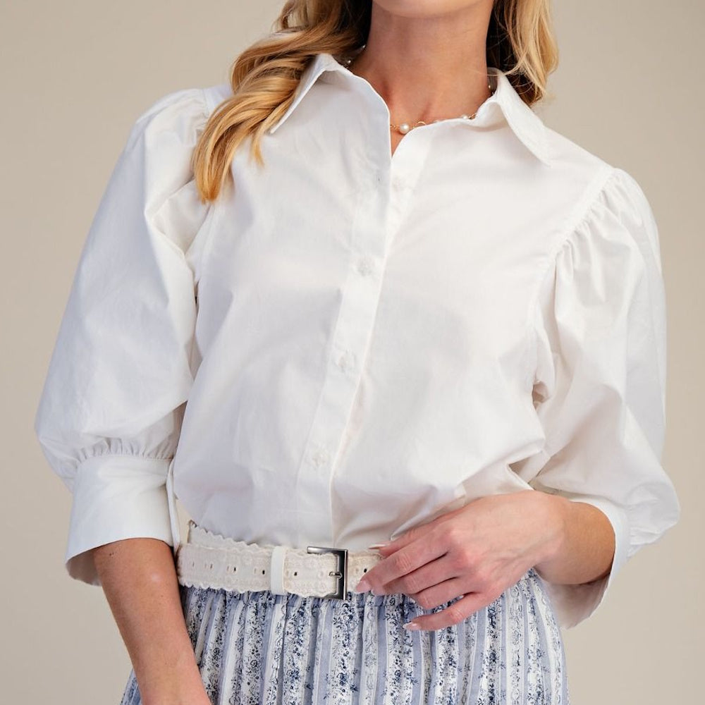 Woman wearing a white button-down shirt with puff sleeves and a classic collar.