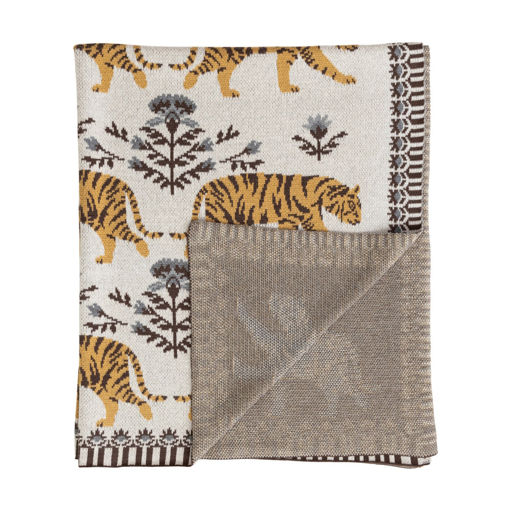 Cream knit throw blanket with orange tiger pattern and grey floral accents, featuring a folded corner revealing grey back.