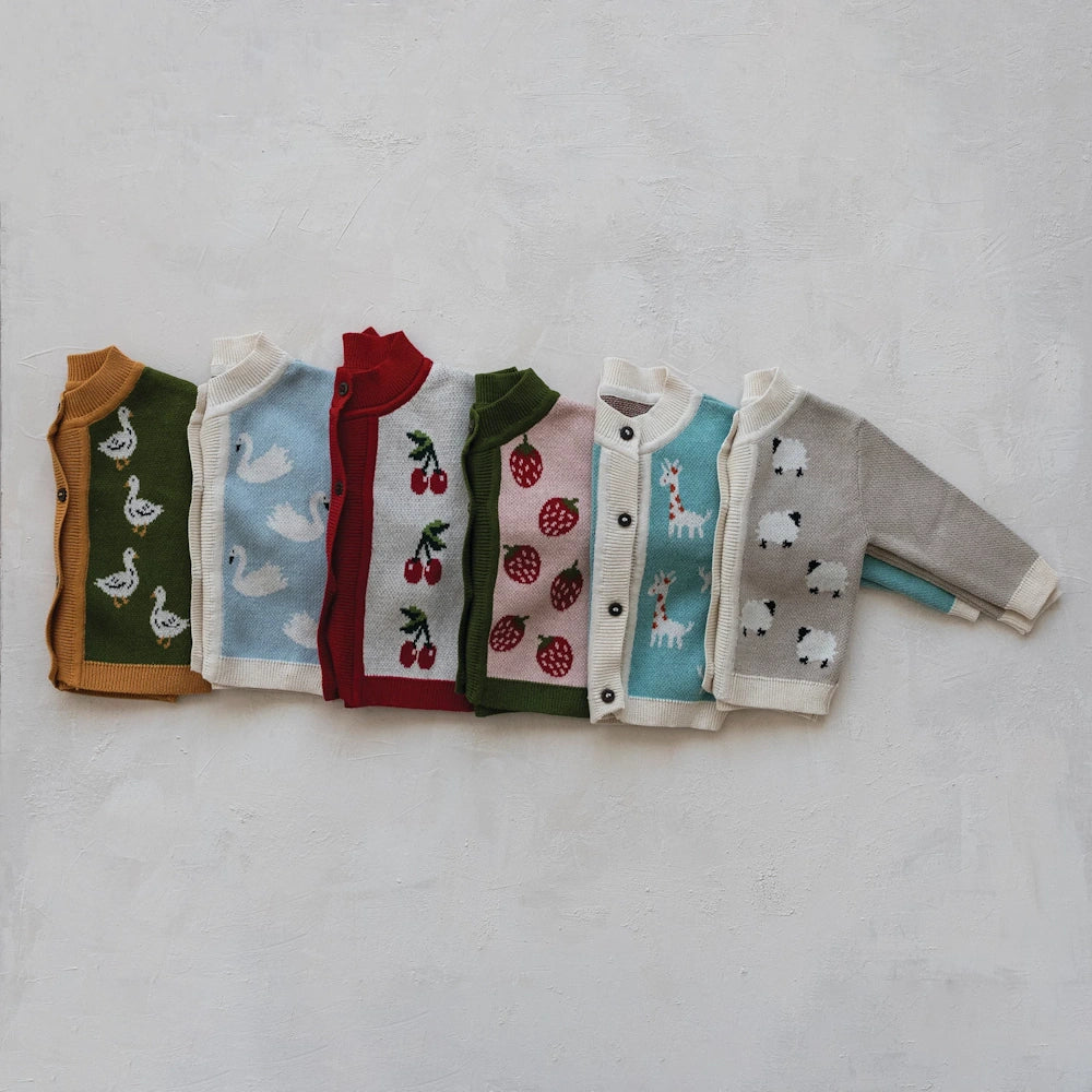 Assorted cotton knit baby cardigans with animal and fruit patterns, wood buttons, and ribbed trim on a white background.