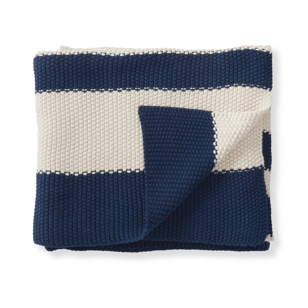 Folded navy blue and white striped chunky knit throw blanket on a white background.
