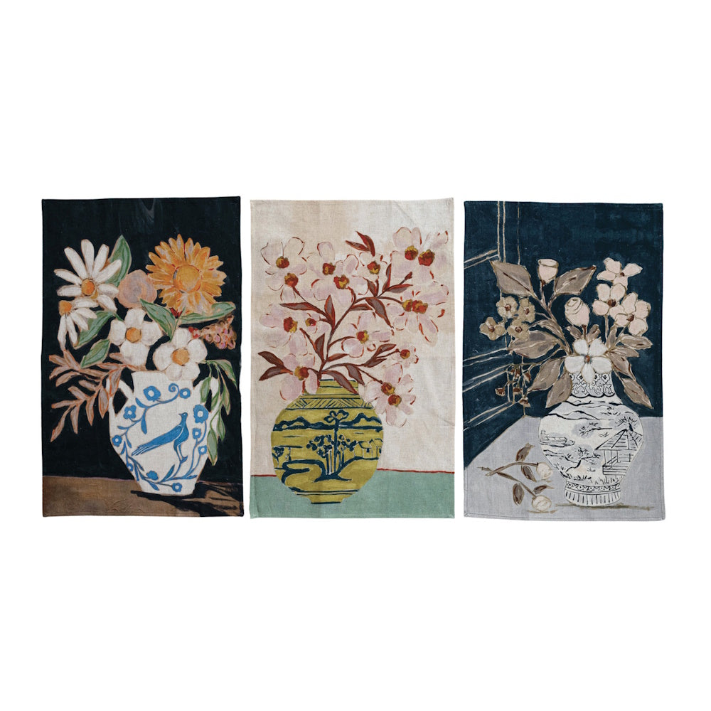 Three cotton-linen tea towels side-by-side, each printed with an illustration of flowers in a decorative vase.