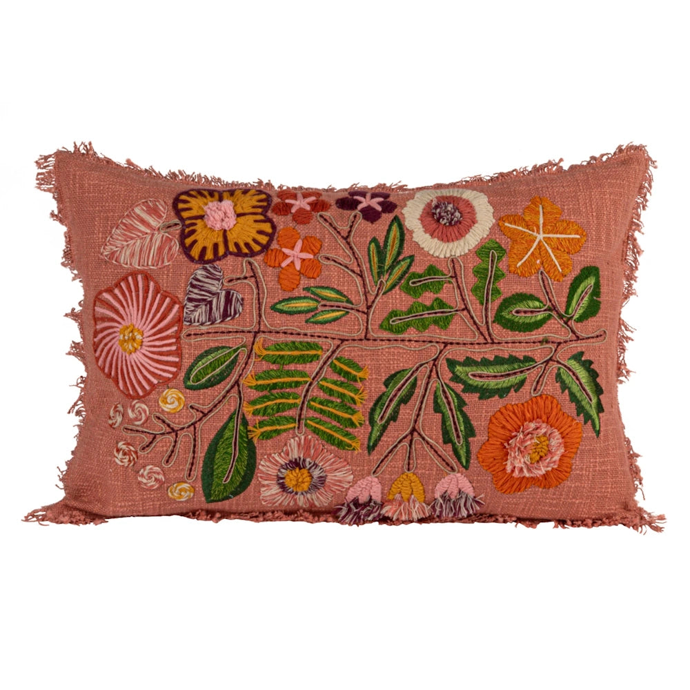 Embroidered floral lumbar pillow with colorful botanical patterns and fringed edges on terracotta textured fabric.
