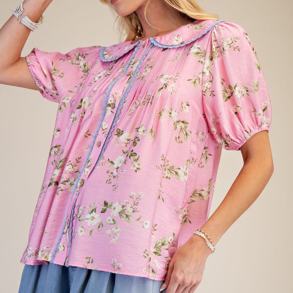 Pink floral print short-sleeve button-up top with a blue lace-trimmed Peter Pan collar and puffed sleeves.