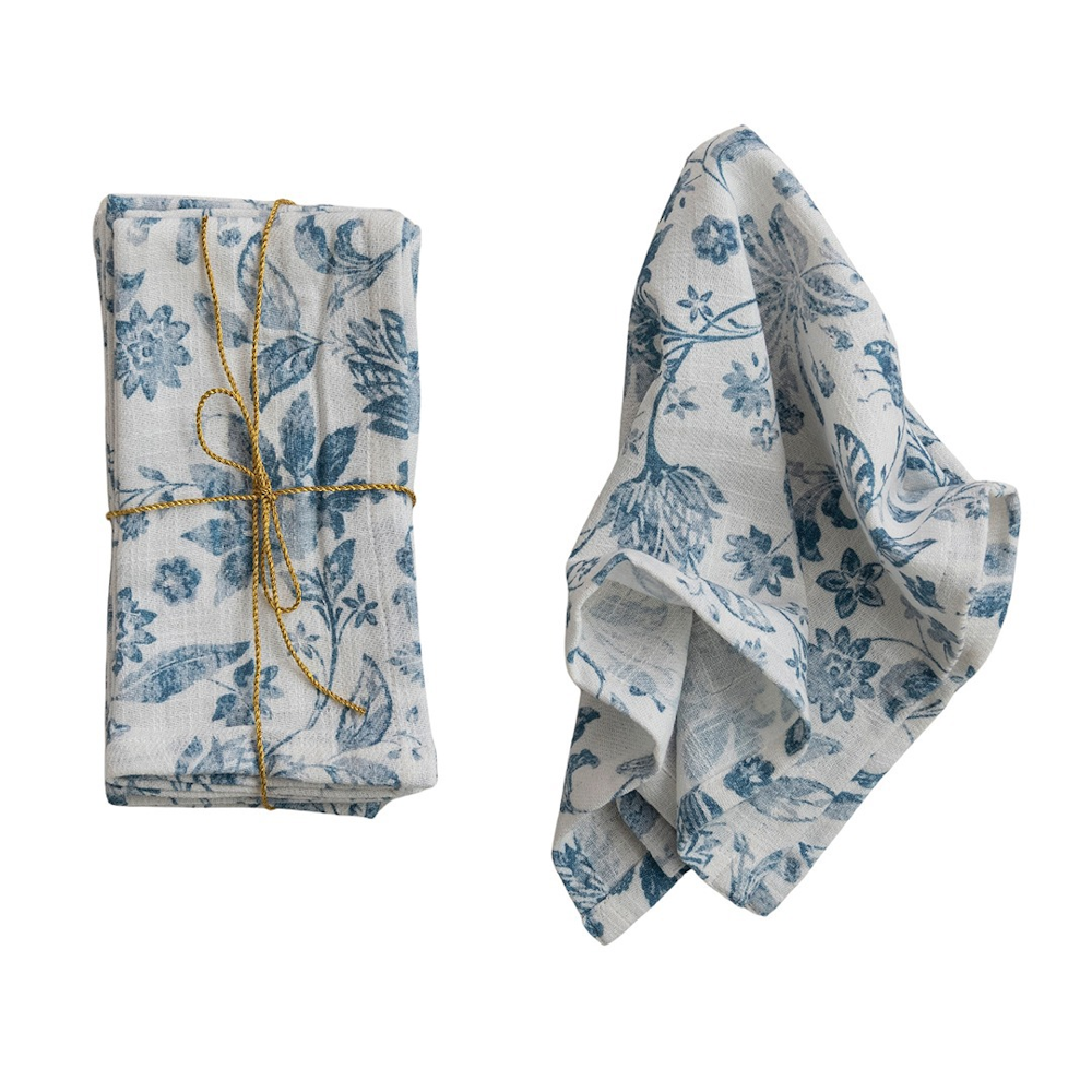 White cotton cloth napkins with blue floral prints, one neatly tied with twine and one loosely draped.