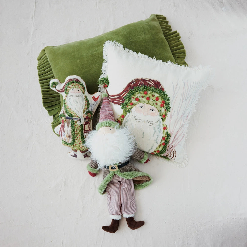 Festive Christmas decor collection featuring Santa embroidered pillows, a green velvet cushion, and a gnome plush.