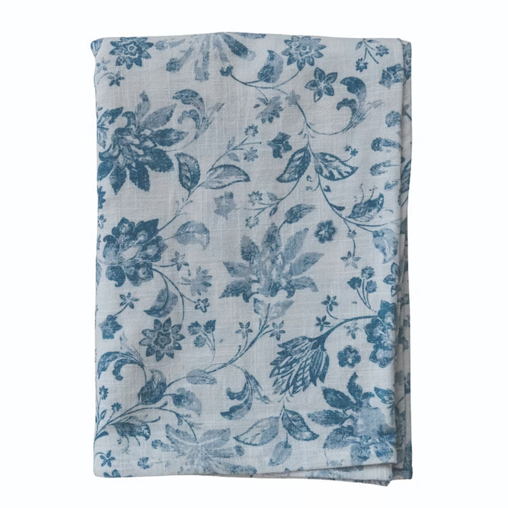 Folded white cloth fabric featuring a blue floral and botanical vine pattern printed throughout.