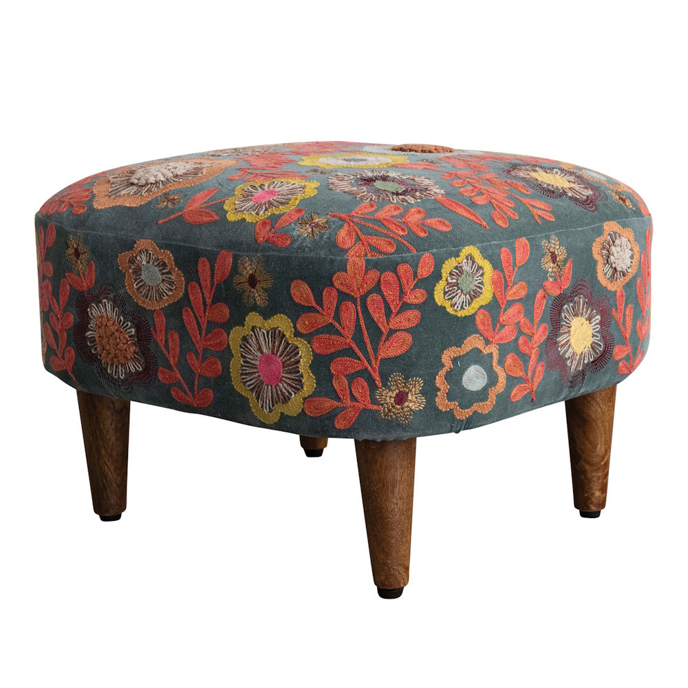 Round velvet ottoman stool with colorful floral embroidery and short wooden legs.