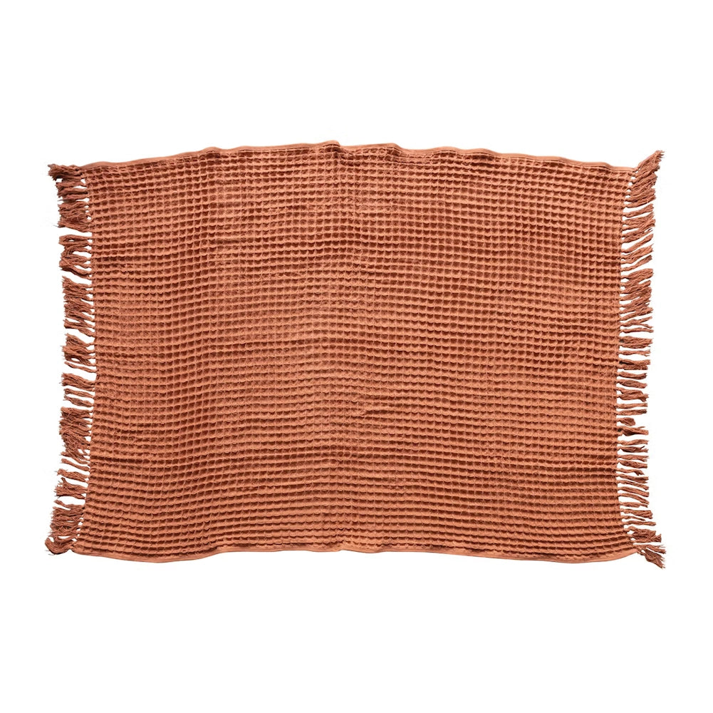 Terracotta orange cotton waffle weave throw blanket with fringe trim.